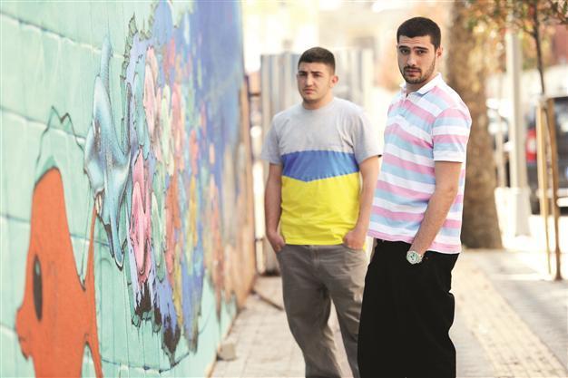 Two young men paint city walls as a business