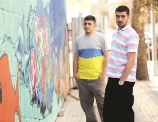 Two young men paint city walls as a business