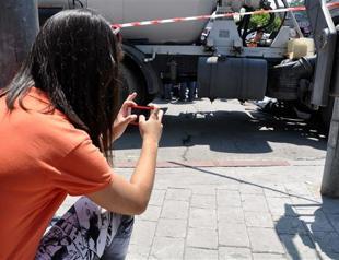 Passersby crowd around to snap photos of accident victim