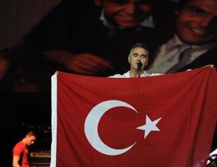 Morrissey’s band appears on stage in anti-Assad t-shirts