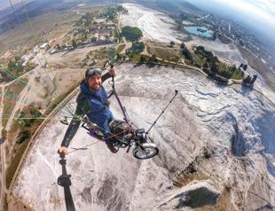 Paraglider flies with bike over Pamukkale