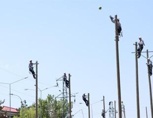 Electricians playing volleyball on top of poles for balance training