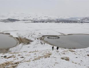 People walk to castle in middle of lake as water ebbs