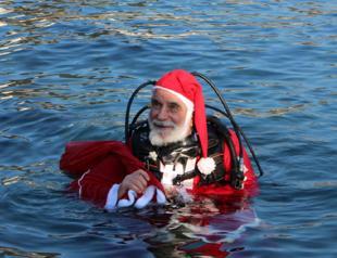 Diver in Santa Claus outfit collects plastic fish