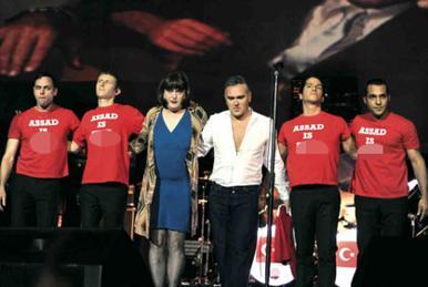 Morrissey’s band appears on stage in anti-Assad t-shirts
