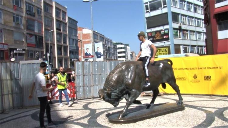 Kadıköy’de bakıma alınan Boğa Heykeli’nin üzerine çıkıp fotoğraf çektirdi