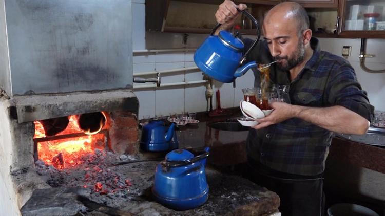 Çay taleplerine yetişmek için ağzında süzgeçle bardakları dolduruyor