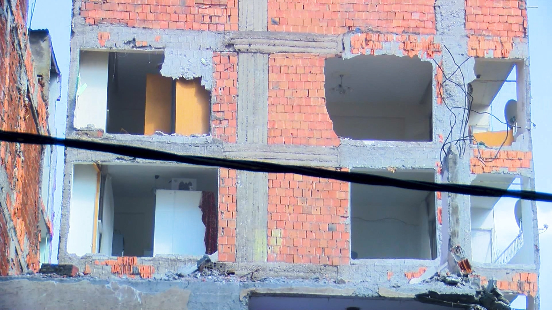 Depremde ağır hasar alan bina yıkıldı, bitişikteki apartmanın bazı odaları duvarsız kaldı Mecburen bu hasarlı evin içinde kalıyoruz