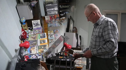 Çocuk yaşta harçlıklarıyla biriktirmeye başladığı binlerce plağına özenle bakıyor