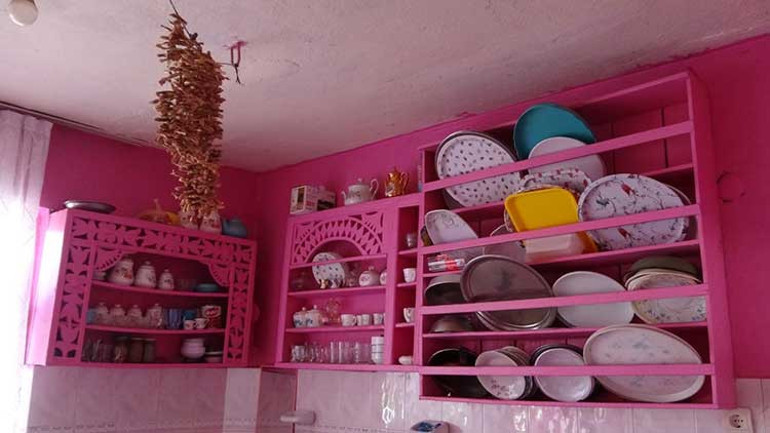 Pembe evinin önünde oturan yaşlı kadın