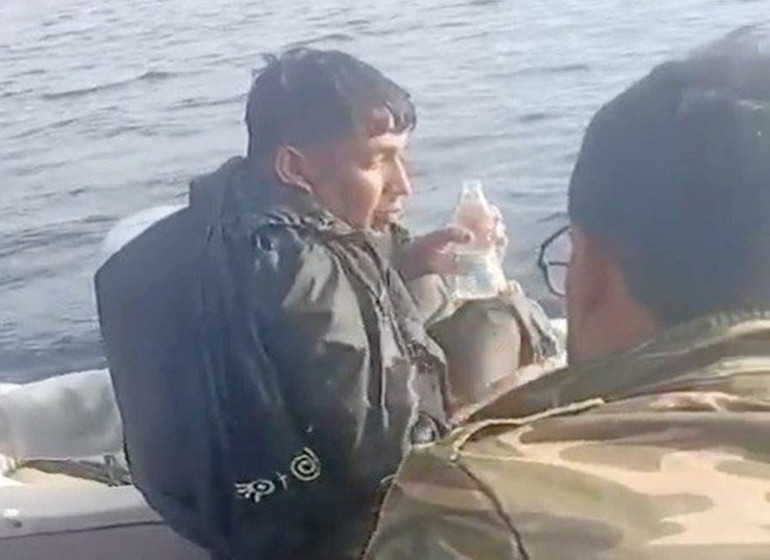 Denizde çırpınan göçmenin tekneye alınması