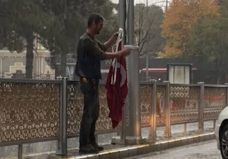 Yağmur altında yere düşen bayrakları toplayan kişi