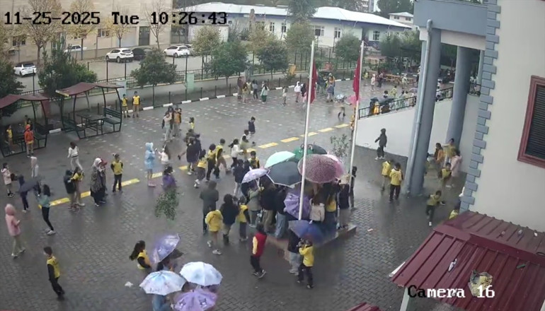 İlkokul öğrencileri yağmur altında Atatürk büstünü şemsiyeyle koruyor