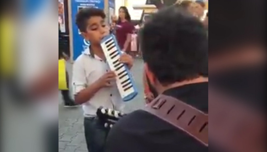 Üsküdarda enstrümanı ile sokak sanatçılarına eşlik eden çocuk