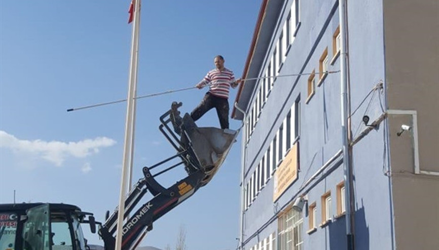 Okul müdürü, kepçenin kovasına binip okulu boyadı