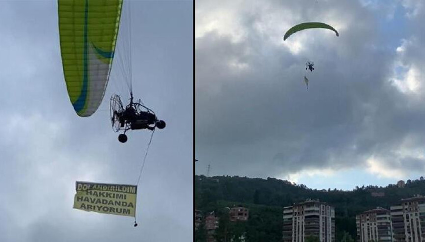 Kiraladığı paramotorla Dolandırıldım, hakkımı arıyorum yazılı afişle uçtu