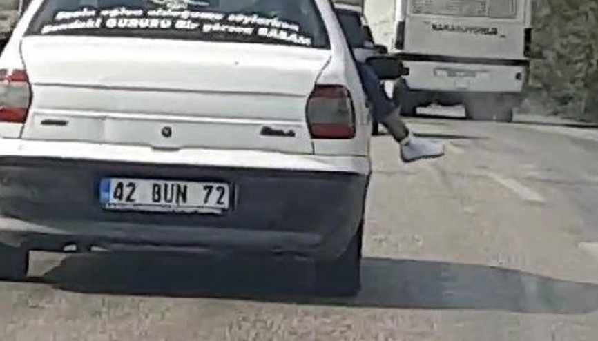Görenler hayrete düştü Seyir halindeki araçtan ayaklarını sarkıttı