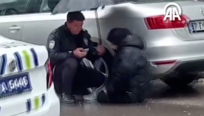 Polis, yaralanan yayanın başında ıslanmasın diye şemsiyeyle bekledi
