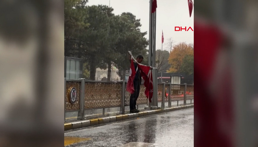Yağmura aldırış etmeden yere düşmek üzere olan Türk bayraklarını toplayan vatandaş duygulandırdı