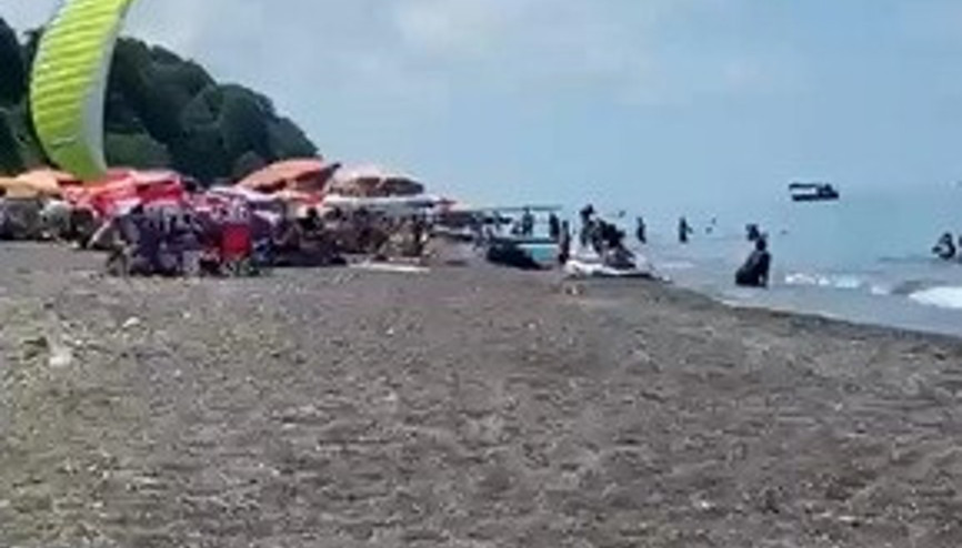 Sahilde motorlu yamaç paraşütüyle havalanırken tatilcilerin arasına daldı